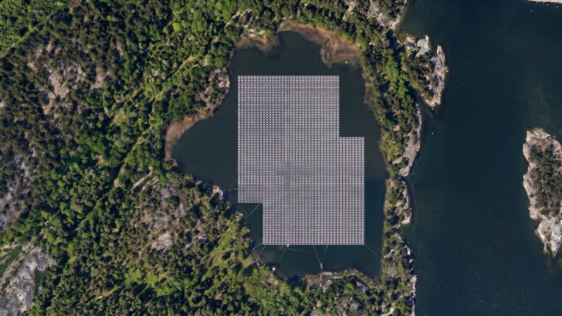 Stor flytande solpark på en skogssjö vid kusten, sett rakt ovanifrån